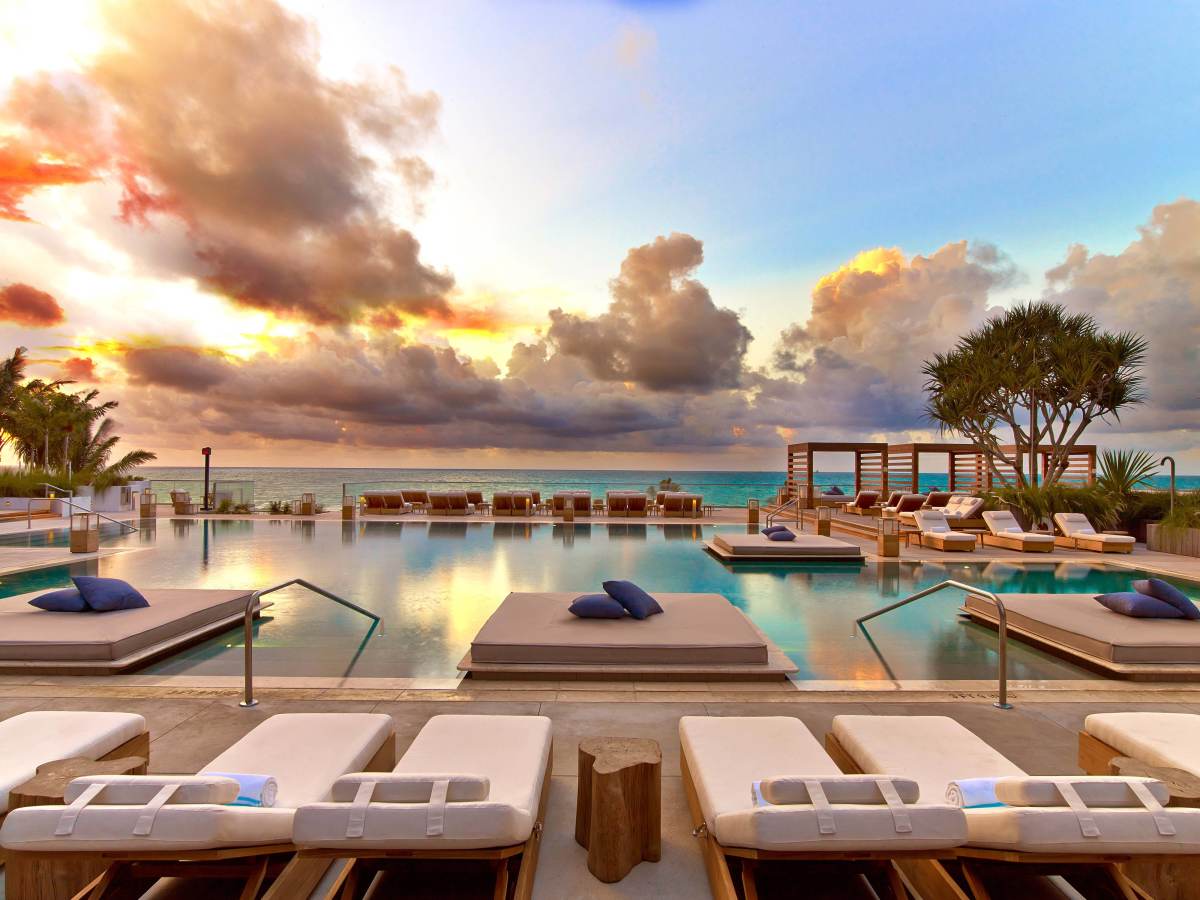 Piscine principale du 1 Hotel South Beach au coucher du soleil, daybeds dans l'eau face à l'océan